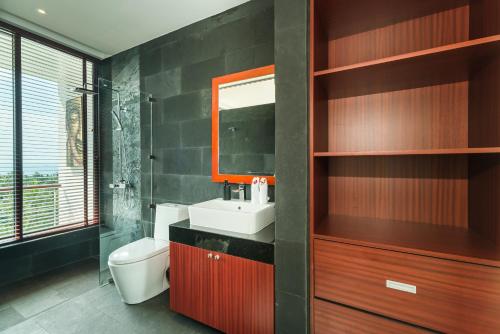 een badkamer met een wastafel, een toilet en een spiegel bij Villa Tosti in Ban Bang Po