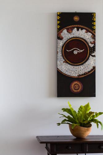 a painting on a wall next to a table with a plant at Villa Tosti in Ban Bang Po