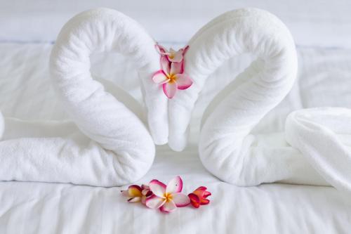 a couple of white towels and flowers on a bed at Villa Tosti in Ban Bang Po
