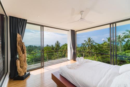 a bedroom with a bed and large windows at Villa Tosti in Ban Bang Po