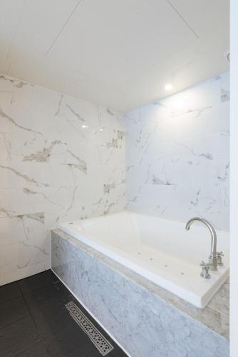 a white bath tub in a bathroom with marble walls at Boutique Hotel XYM Pyeongtaek in Pyeongtaek