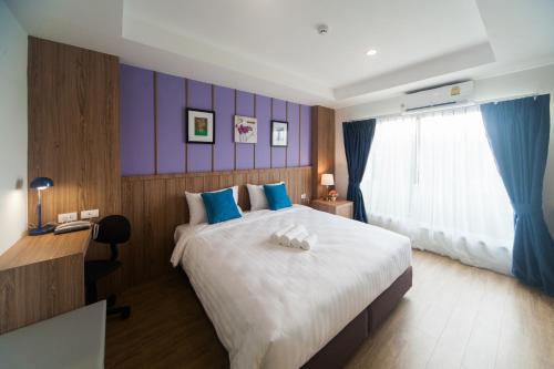 a bedroom with a large bed with blue and purple walls at Anchan Laguna Hotel โรงแรมอัญชันลากูน่า in Khon Kaen