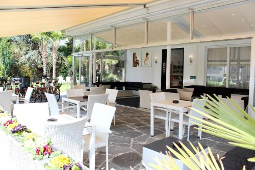 阿斯科納的住宿－盧納加爾尼酒店，餐厅设有白色的椅子和桌子以及窗户。