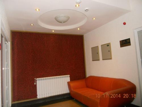 a living room with an orange couch and a red wall at Family Hotel Helios in Sevlievo