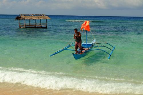 a man standing on a boat in the ocean at White Beach Front and Cottages in Buruanga