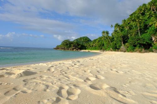 a beach with footprints in the sand and the ocean at White Beach Front and Cottages in Buruanga