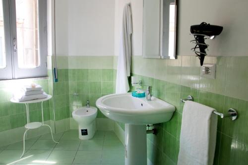 a green and white bathroom with a sink and a toilet at Il Centenario in Ascea