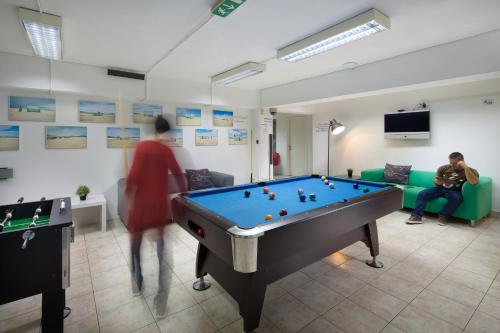 a room with a pool table and a man sitting on a couch at Hostel Bureau in Zagreb
