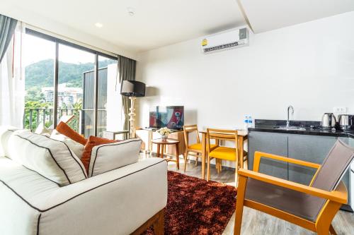 a living room with a white couch and a kitchen at The Deck Condominium by Lofty in Patong Beach