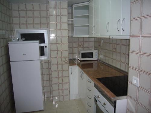 eine Küche mit einem weißen Kühlschrank und einer Mikrowelle in der Unterkunft Ocean 3 - Fincas Arena in Benidorm