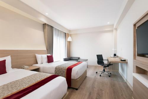 a hotel room with two beds and a desk at Oaks Bodhgaya in Bodh Gaya