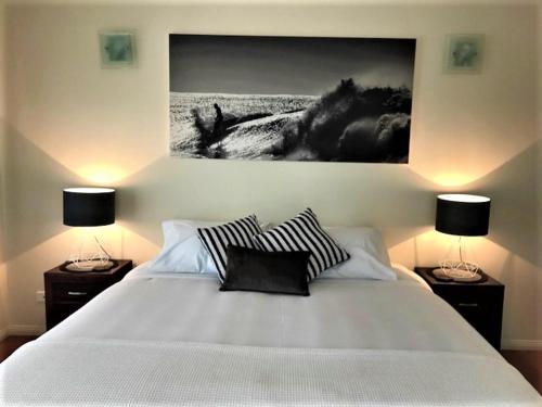a bedroom with a large white bed with two lamps at Compass Point 8 in Hamilton Island