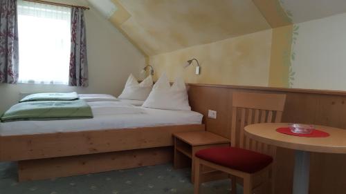 a bedroom with a bed with a red chair and a table at Landhaus Neubauer in Millstatt