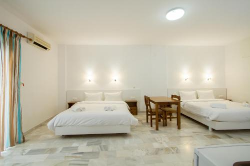 a white room with two beds and a table at Revekka Rooms in Kissamos