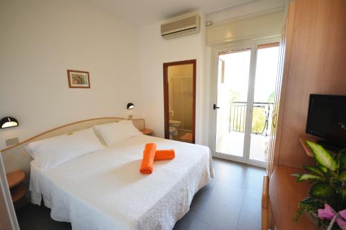 Un dormitorio con una cama blanca con un objeto naranja. en Hotel Apollo, en Cesenatico