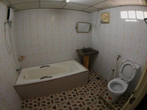 PuengLuang Hotel في دامنون سادواك: حمام مع حوض استحمام ومرحاض
