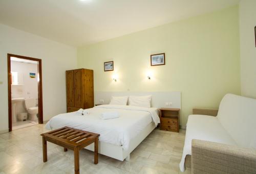 a bedroom with a large white bed and a couch at Revekka Rooms in Kissamos