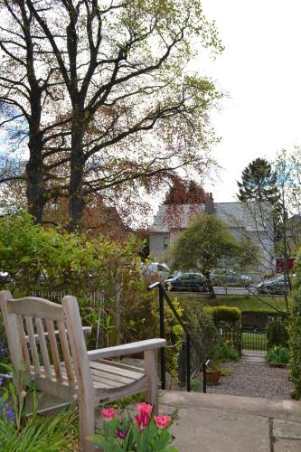 a wooden bench sitting in a garden with flowers at The Spindle Guest Rooms in St. Andrews