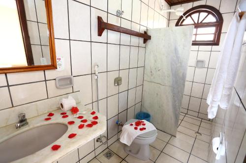 a bathroom with a toilet and a sink with flowers on it at Andimar Hotel in Porto Seguro