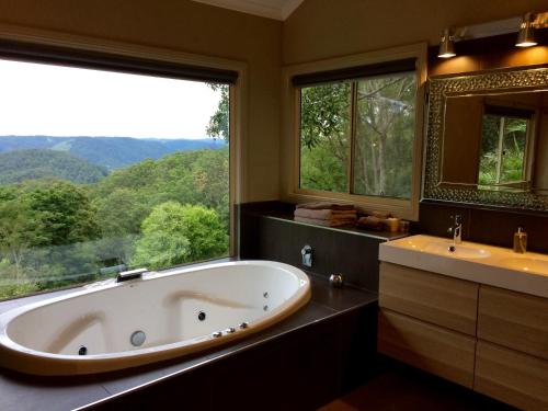 a large bath tub in a bathroom with a large window at Maleny Luxury Cottages in Maleny