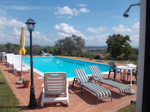 ein Pool mit einem Haufen Stühle und einer Laterne in der Unterkunft Le Pergoline B&B in Casciana Terme