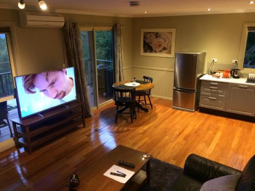 a living room with a flat screen tv and a kitchen at Maleny Luxury Cottages in Maleny
