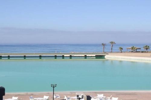 a swimming pool next to the beach with the ocean at Cabo de Gata Oasis Retamar in El Toyo