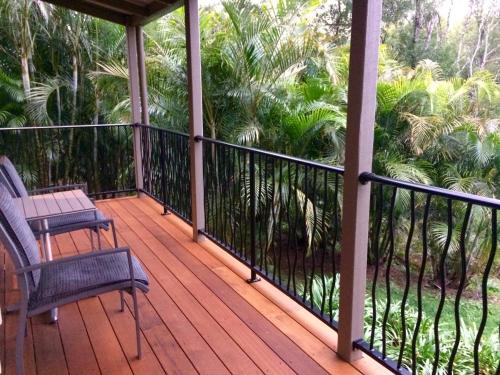 a porch with two chairs and palm trees at Maleny Luxury Cottages in Maleny