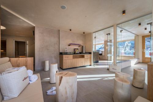 a living room with wooden stools and a kitchen at Hotel Alpenrose in Pertisau