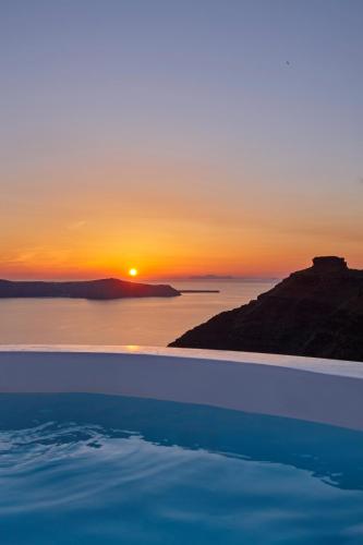 a sunset over the ocean with a swimming pool at Nautilus Villa in Firostefani
