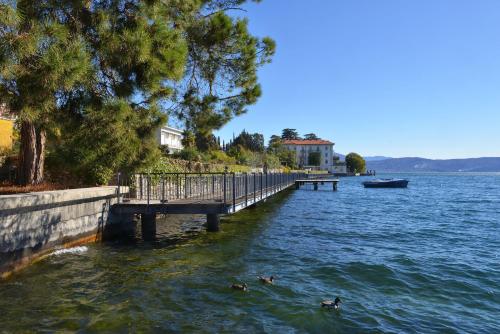 three ducks swimming in the water near a dock at Taverna Affittacamere in Gardone Riviera