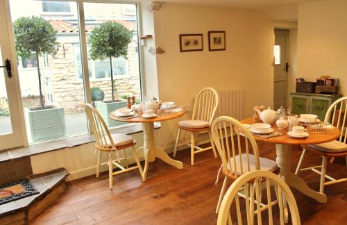 uma sala de jantar com duas mesas e cadeiras e uma janela em The Barn em Monk Fryston