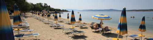 a beach with many chairs and umbrellas and the water at Apartments Sax in Crikvenica