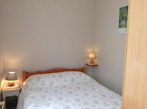 a bedroom with a bed and two lamps on tables at Au Bon Gite - Studio in Arromanches-les-Bains