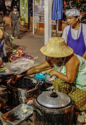 a woman wearing a straw hat cooking in a stove at Thanawong Pool Villa in Sukhothai