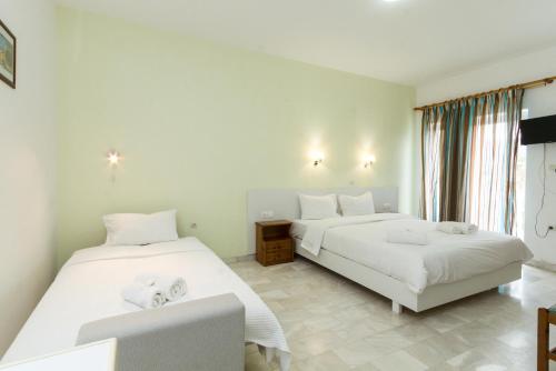 a bedroom with two beds and a window at Revekka Rooms in Kissamos