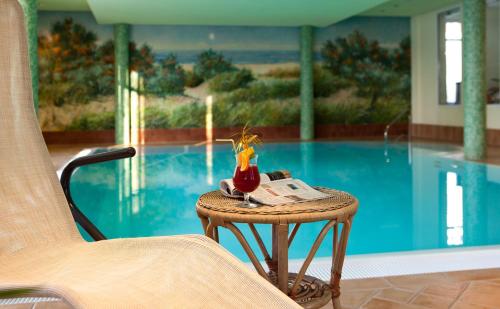 a table with a drink on it next to a pool at Am Weststrand Apartmenthaus Bellamare in Kühlungsborn