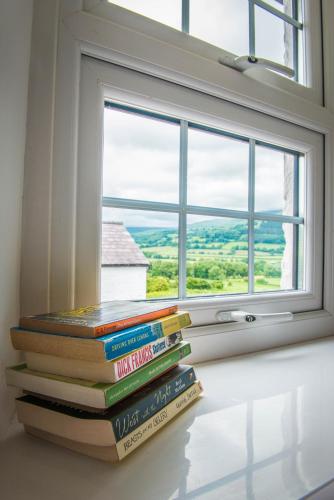 a stack of books sitting in front of a window at The Kestrel B&B in Crickhowell