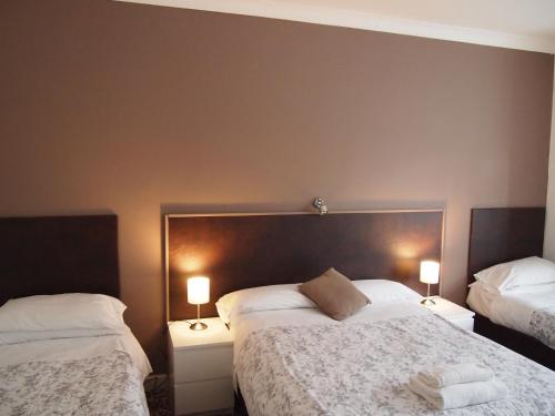 um quarto com 2 camas e 2 candeeiros nas mesas em Kingswood Hotel em Maidenhead