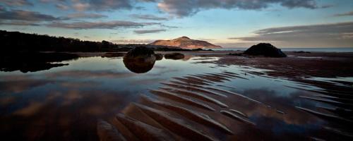 a reflection of a mountain in a body of water at Cruickshanks Boutique B&B in Whiting Bay