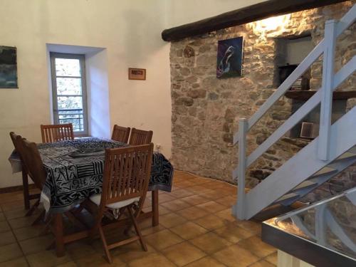 Un comedor con una mesa y una pared de piedra. en Maison Ancienne Minervois, en La Caunette