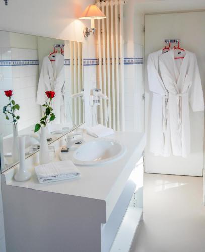 une salle de bain blanche avec un lavabo et un miroir dans l'établissement Maison d'Hôtes l'Escale, à Bains-les-Bains