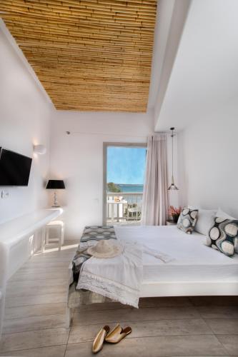 a white bedroom with a large bed and a window at Thomais Studios in Naxos Chora