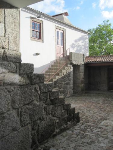 a stone retaining wall next to a white house at Casa da Torre in Sobrosa