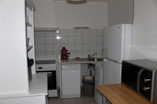 eine weiße Küche mit Spüle und Kühlschrank in der Unterkunft maison de bourg in Talmont
