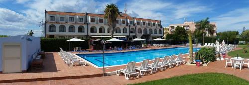 Hotel Relax في سيراكوزا: فندق فيه مسبح وكراسي ومبنى