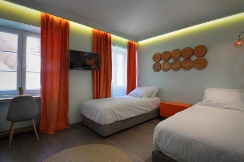 a room with two beds and a window with orange curtains at Locandiera in Corfu Town