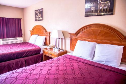 um quarto de hotel com duas camas com lençóis roxos em Albany Inn & RV Campground em Albany