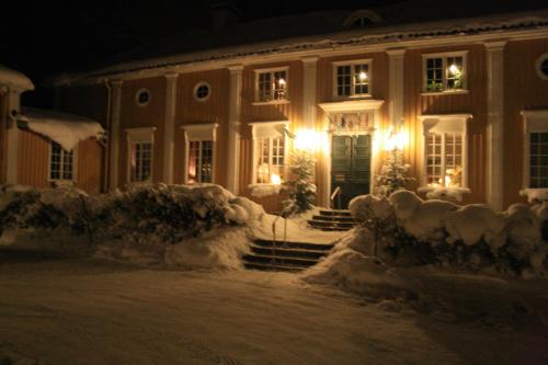a house covered in snow at night with lights at Forsbacka Wärdshus in Forsbacka