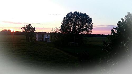 a house in the middle of a field at sunset at B&B La Casa di Klida in Minerbio